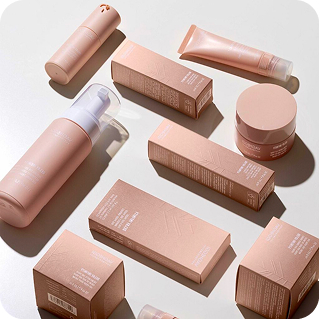 Rose-gold skincare product boxes and jars on a neutral background