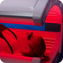 Person receiving red LED light therapy under a canopy bed