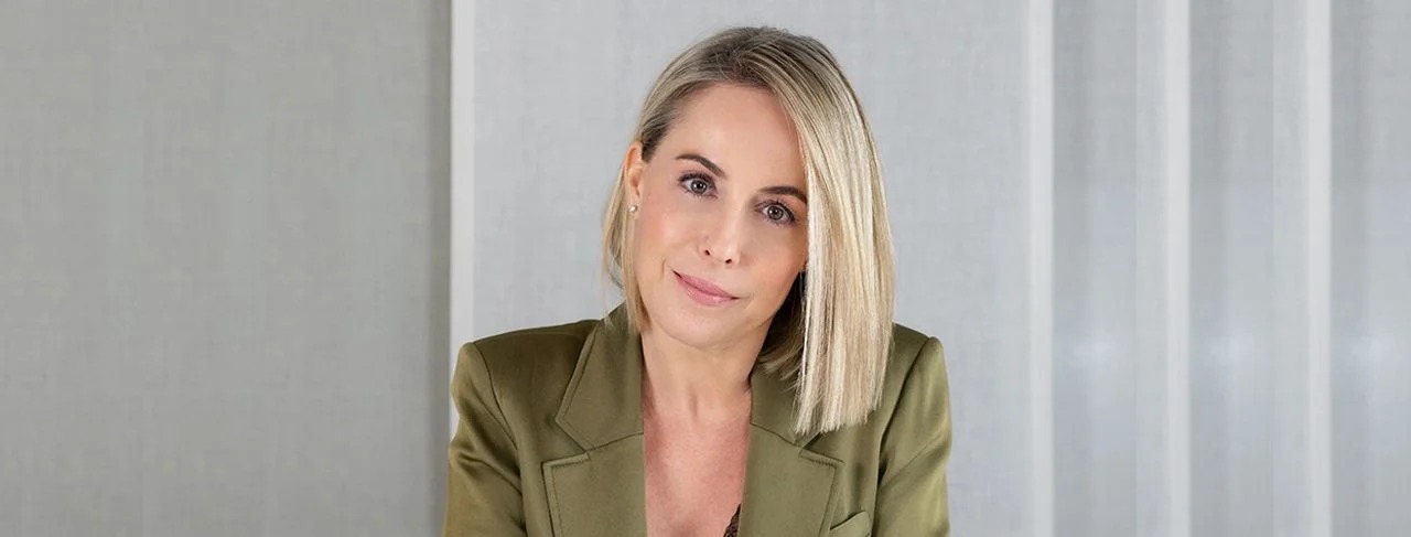 Portrait of a blonde woman in an olive green blazer